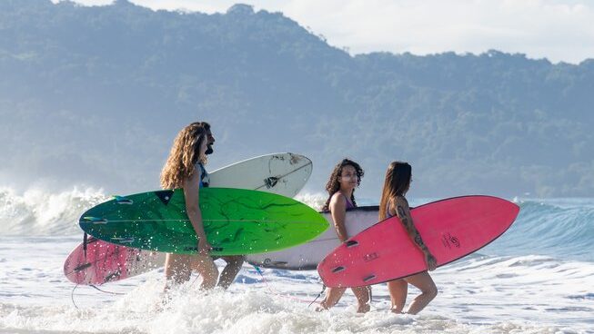 A group of surfers entering the ocean with surfboards at Akih Pods Hostel in Santa Teresa