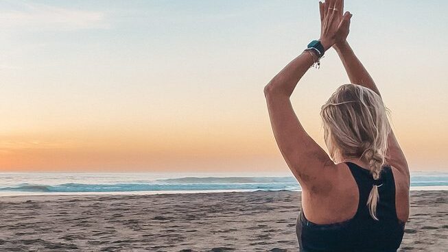 a person doing yoga by the beach at sunset at Del Alma Retreat Costa Rica surf camp