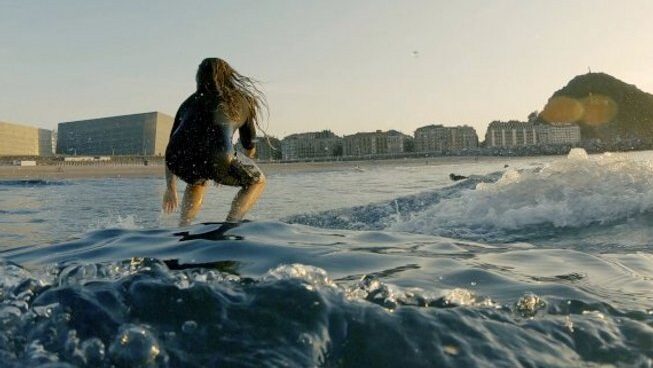 A surfer riding a wave at El Aula Azul surf camp in San Sebastian