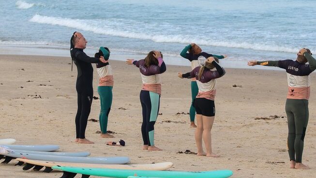people stretching at the beach before going surfing at Ferrel Surf House surf camp in Peniche Portugal