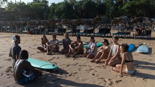 learner surfers listening to instructor on the beach at Global Surf Lodge Kabalana Surf Camp