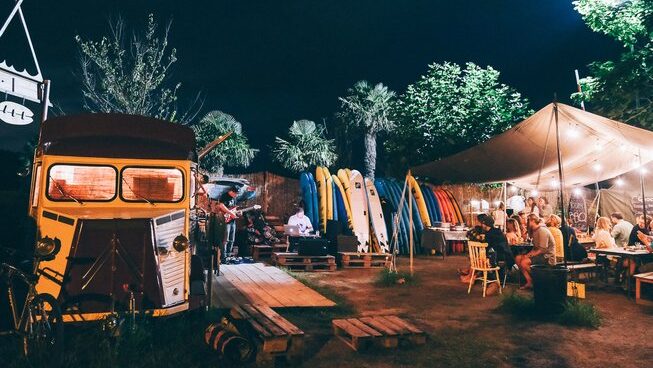 A group of people having dinner under light at Good People Surf surf camp in Zarautz