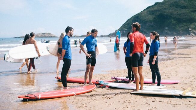 A group of people listening to the surf instructor at Good People Surf surf camp in Zarautz