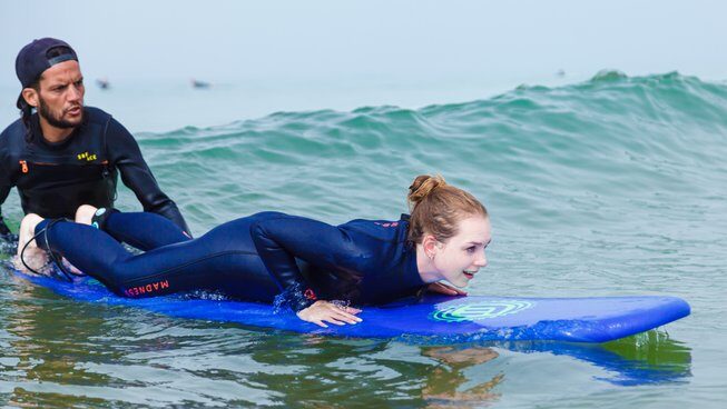a learner surfer getting pushed on a wave at Hola Surf Hostel Surf camp
