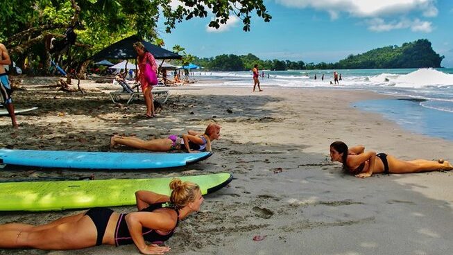 people learning how to surf on the sand at Holis Spa and Wellness Center surf camp in Manuel Antonio