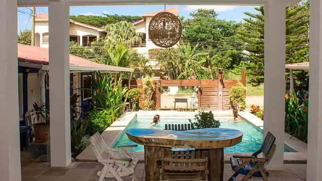 Accomodation with pool and two seats and table at La Botella de Leche surf camp in Tamarindo