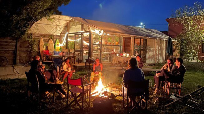 people hanging out at night on chairs with a fire at Maceda Surf Camp in Porto Portugal