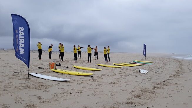 people learning how to surf and stretching on the beach at Marias Hostel & Surf camp in Portugal
