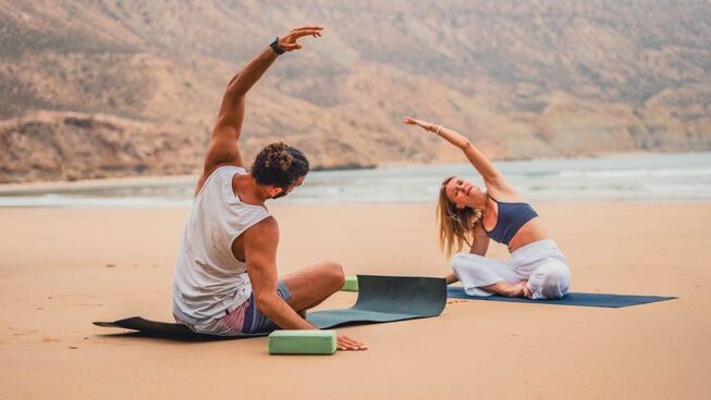 Two people doing yoga on the beach at Olas Surf Ltd Imsouane surf camp