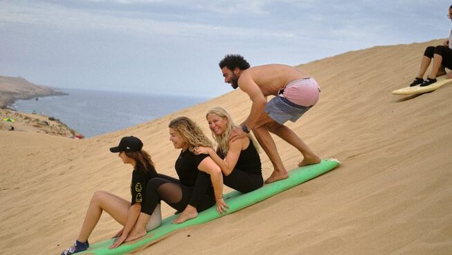 People going down a sand dune with a surfboard at at Olas Surf Ltd Imsouane surf camp