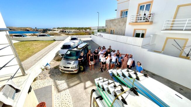Group photo with surfboards on top of car at Peniche Surf Lodge in Portugal