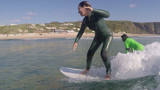 A surfer riding a wave with a learner surf at Portugal Praia das Maçãs Surf Camp in Sintra