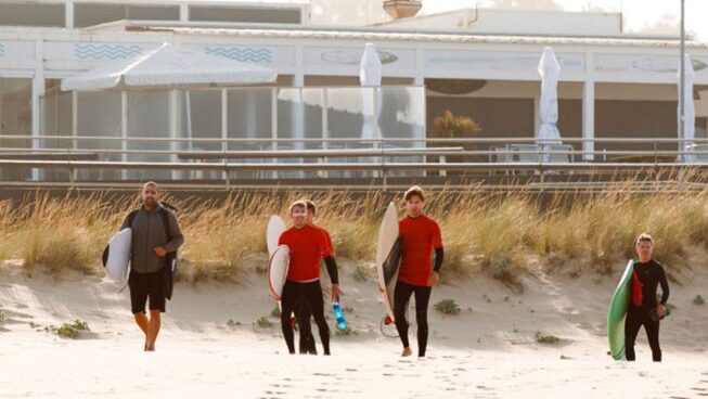 People walking on the beach with surf boards at Sea Krew surf camp