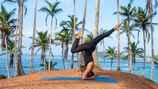A person in a yoga pose with palm trees at Surf & Yoga Mirissa surf retreat