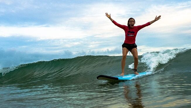 a learner surer standing up on a wave at Surf & Yoga Mirissa surf retreat