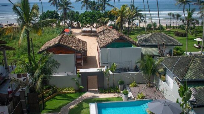 Accommodation and beach view with palm trees at The Greens Room Surf and Yoga Camp Sri Lanka