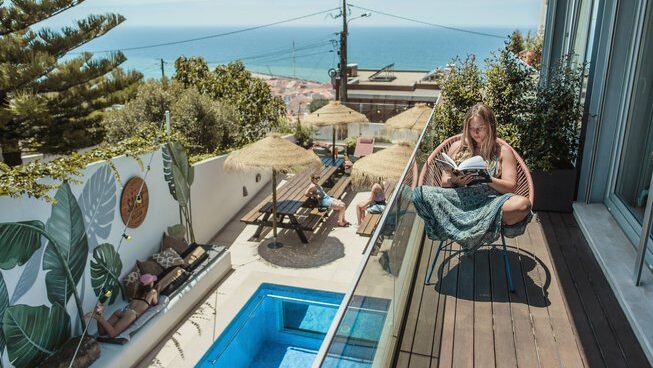 A person reading their book on a balcony at the The Salty Pelican in Ericeira