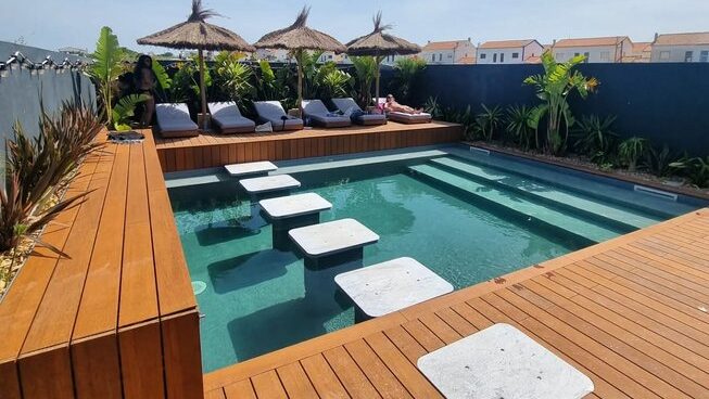 outdoor deck and pool with chairs at The Salty Pelican surf camp in Peniche