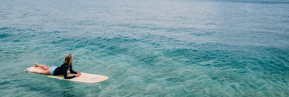 A surfer sitting in the blue water at a best Costa Rica surf camp for beginners