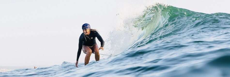 A girl riding a wave at a surf and yoga Peniche camp in Portugal