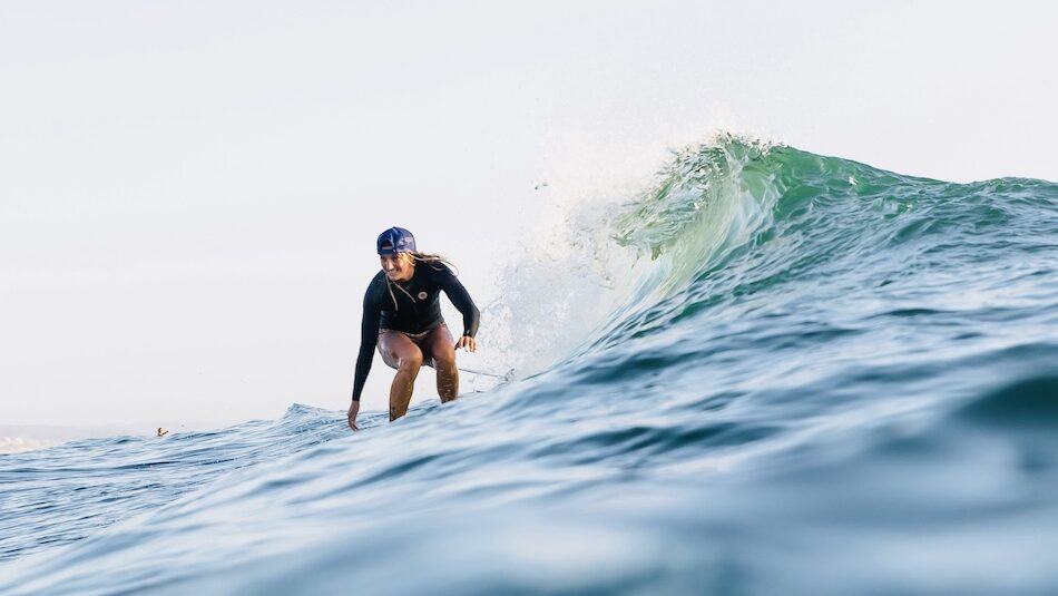 A girl riding a wave at a surf and yoga Peniche camp in Portugal