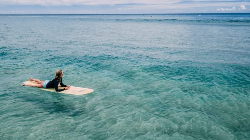 a girl on a surfboard with crystal blue water during a surf camp Portugal beginner