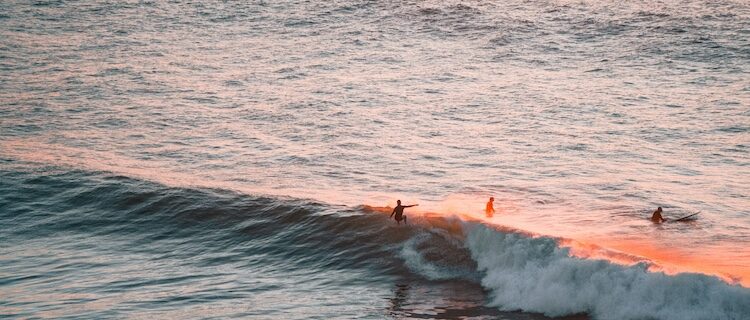 A surfer on a wave with the sun setting at a surf camp near Lisbon
