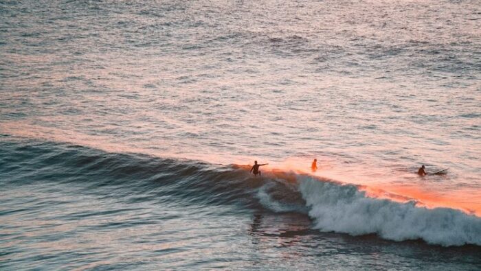 A surfer on a wave with the sun setting at a surf camp near Lisbon