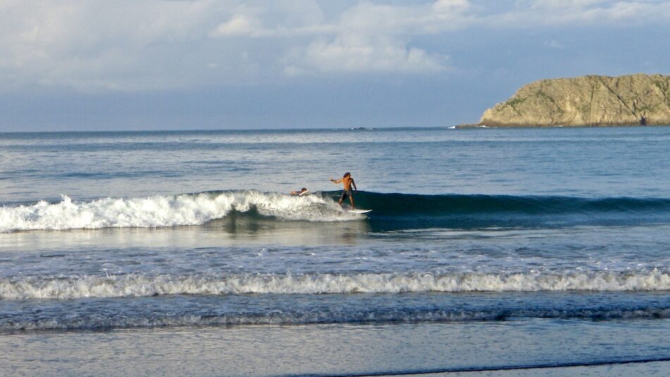 A surfer on a wave at a surf yoga camp Costa Rica