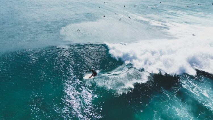 drone shot of a surfer riding a wave at one of the Best Surf Camps In Spain