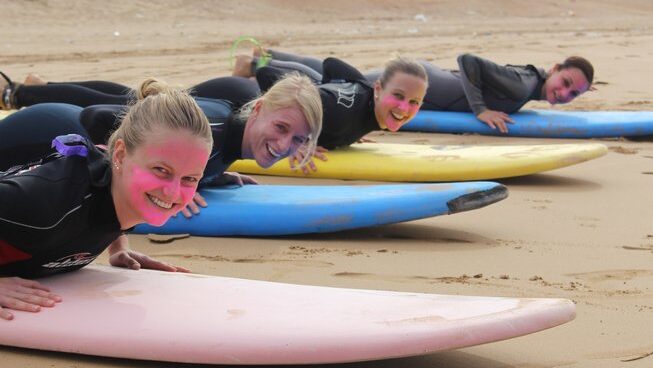 a group of surfers laying on surfboards on the sand with Easy Surf Maroc surf camp