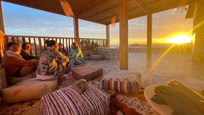 People hanging out at sunset on cushions at Harmony Surf Lodge in Taghazout