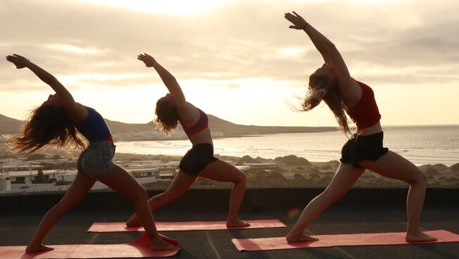 three girls doing yoga on the beach with Lanzasurf surf camp