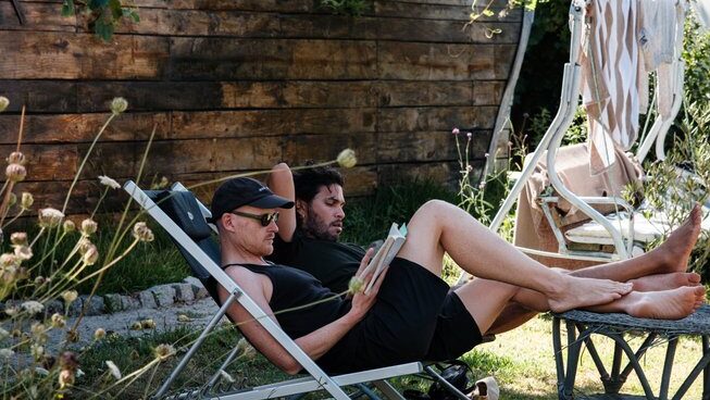 Two people reading a book outside at Maceda Surf Camp in Porto