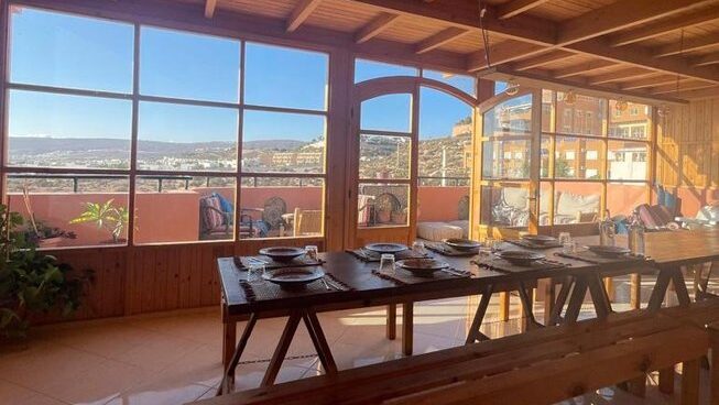 Dining table and sets with a big window at sunset at Moana Surf Maroc surf camp
