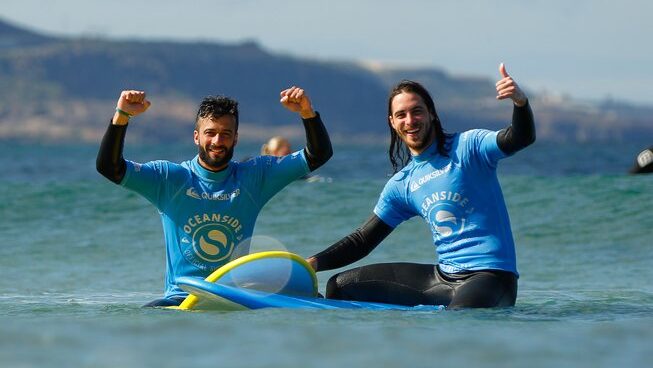 two happy people learning how to surf with Oceanside Gran Canaria Surf camp