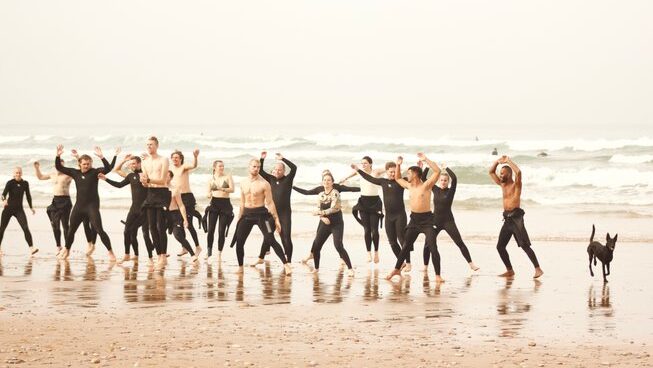 people jumping on the beach with wetsuits at Paddle Out Morocco surf camp