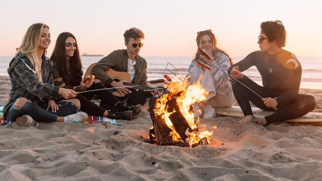 people around a fire with a guitar on the beach at Sand Surf Morocco surf camp