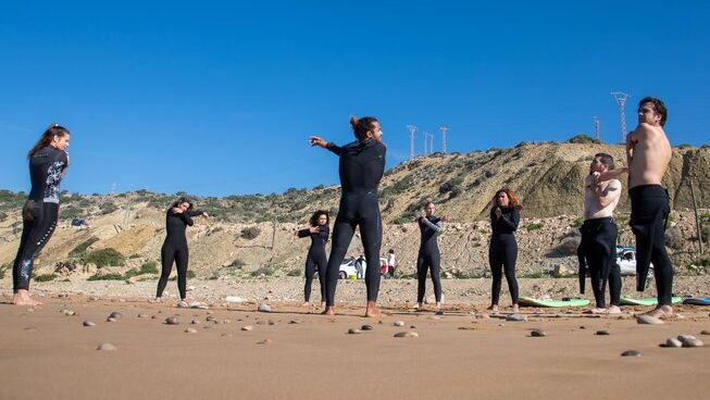 People stretching on the sand at Surf & Travel Camp Morocco