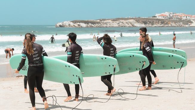learner surfers going for a surf walking on the beach with The Salty Pelican surf Camp Peniche