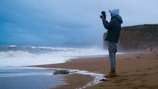 A person with a camera filming the ocean