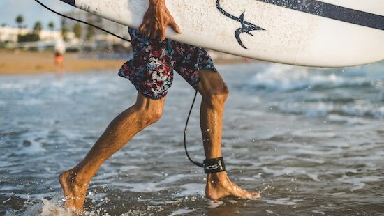 a person with a surfboard and surfboard leg leash heading out in the water