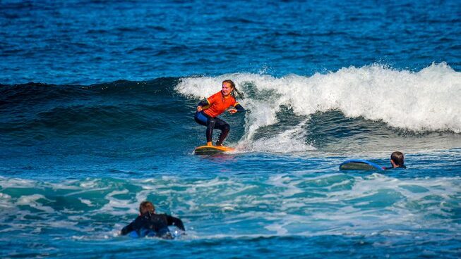 A surfer learning how to ride a wave with Endless Summer Vibes surf camp