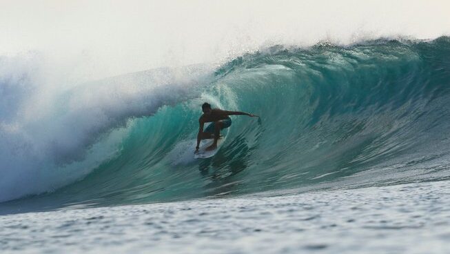 A guy surfing a wave in a barrel with Maki Boat