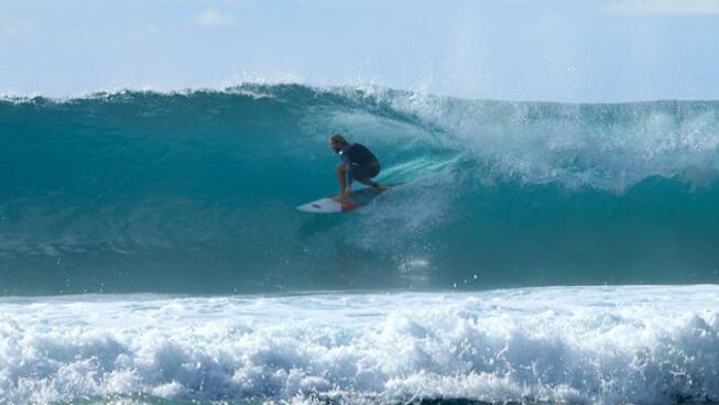 surfer in a blue barrel with Naga Laut surf camp