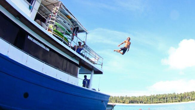 a guy jumping from the boat into the ocean with Naga Laut surf camp Mentawai