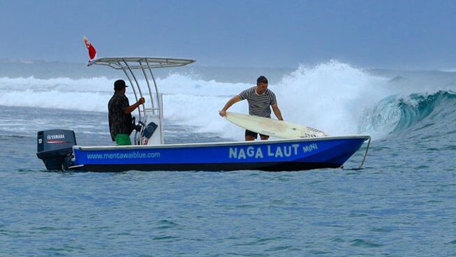 Person unloading surfboard from boat with Naga Laut surf camp Mentawai