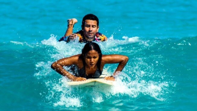 A surfer learning how to surf with an instructor at DHM Surf Camp