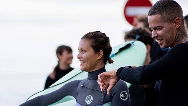 a learner surfer holding a surfboard with Dharmanas Yoga