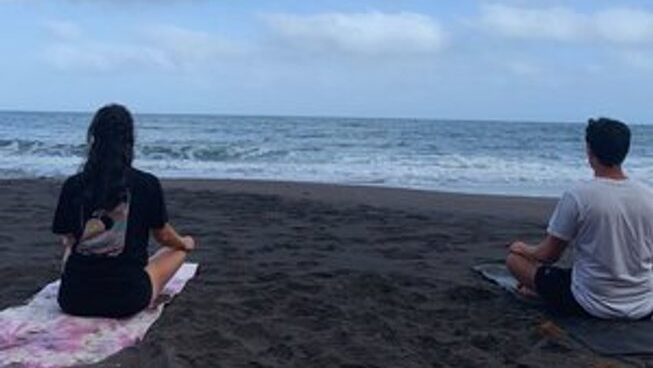 Two people doing yoga at the beach with Dharmanas Yoga
